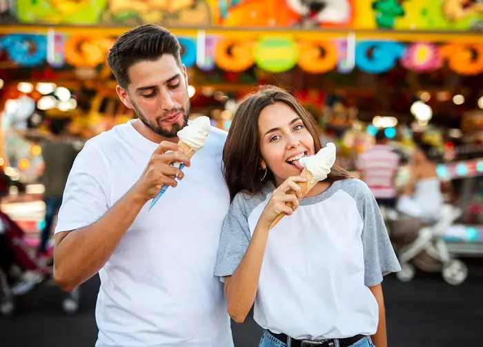 A young pair enjoys ice cream just outside an ice cream parlor. 