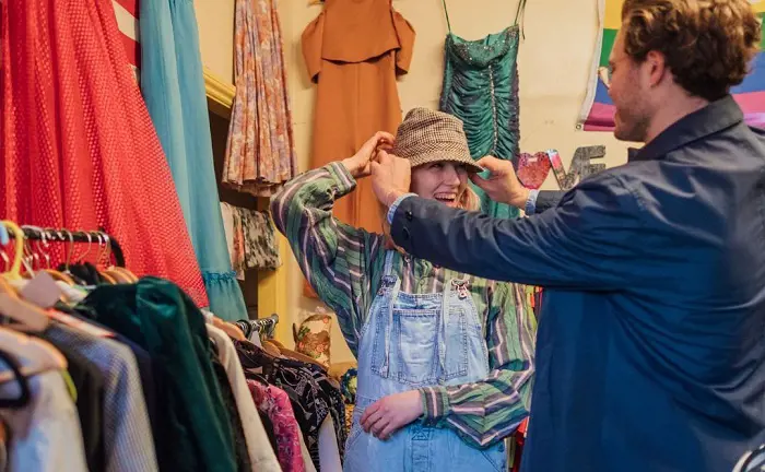 A young couple trying a hat at a thrift store 