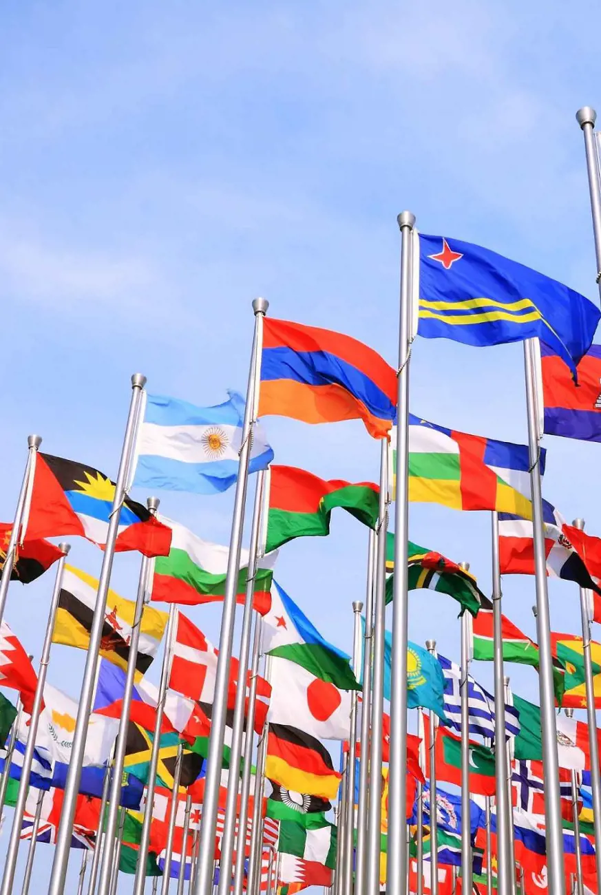 Flags of different countries around the world fly high under the blue sky.