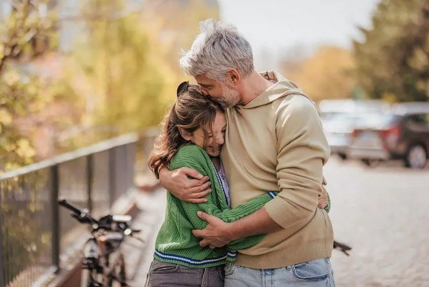 A dad embrace his daughter as they walk outside the town road 