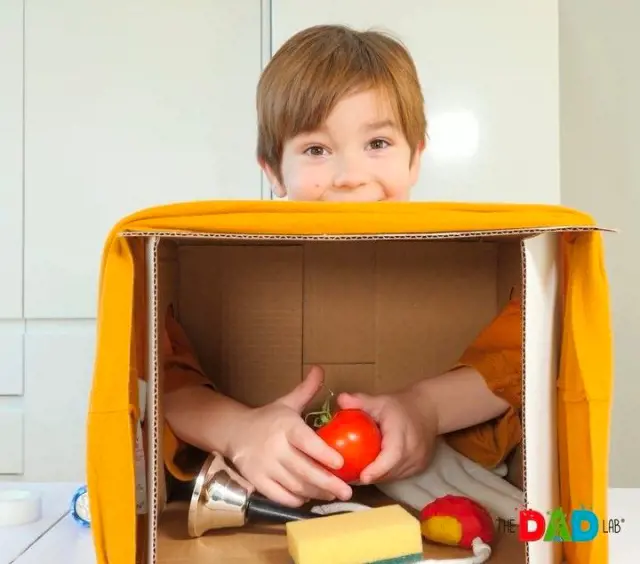 A boy holds an item put inside a box while trying to figure out what it is