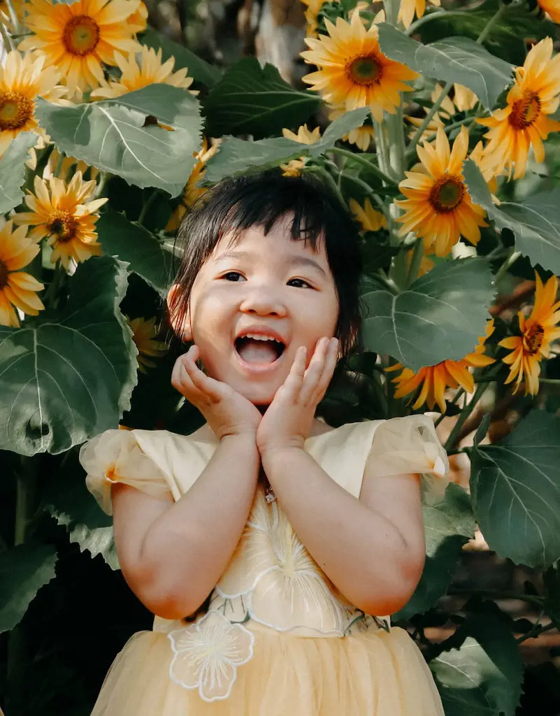 The girl posing near the sunflowers in her yellow dress with a cute pose looks absolutely adorable