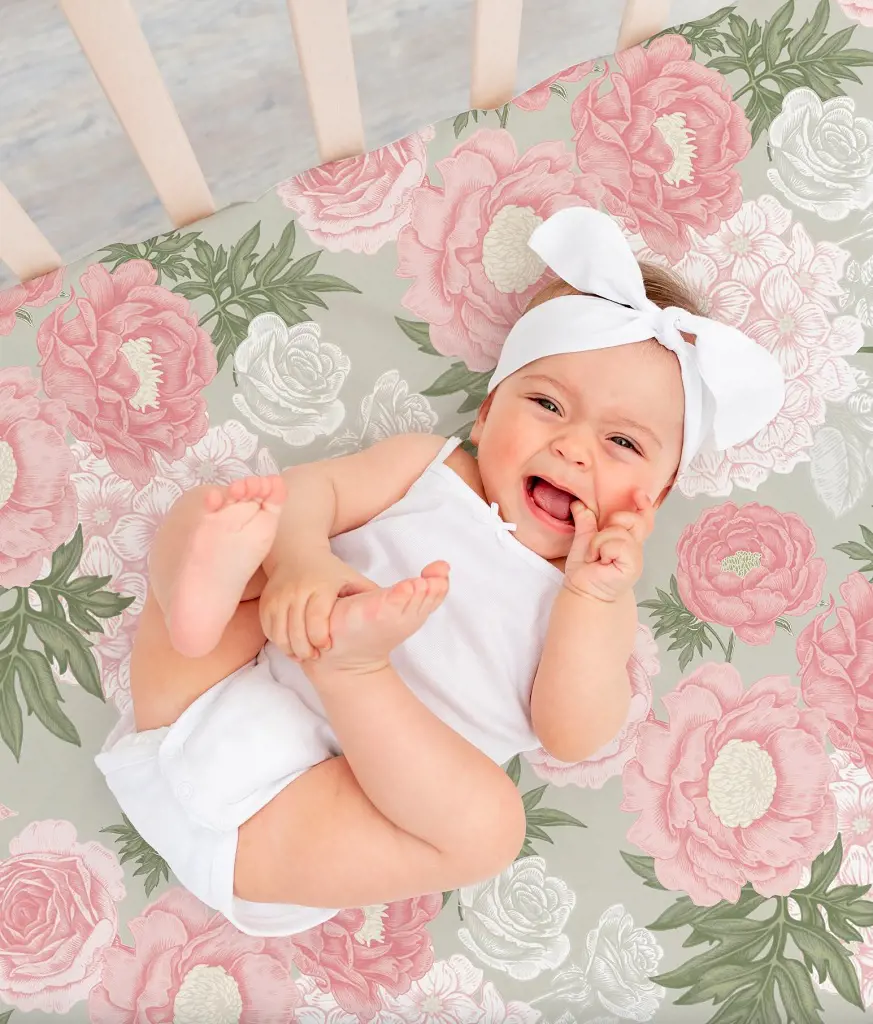 A baby girl peacefully rests in her bed surrounded by the softness of Peony flower bedsheets