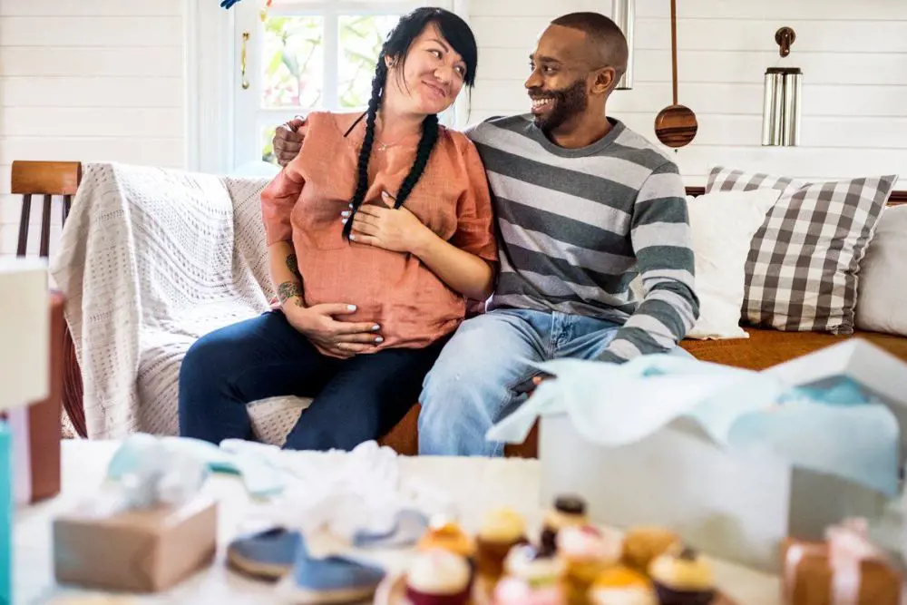 A couple displays a joyous expression as they embrace the baby bump